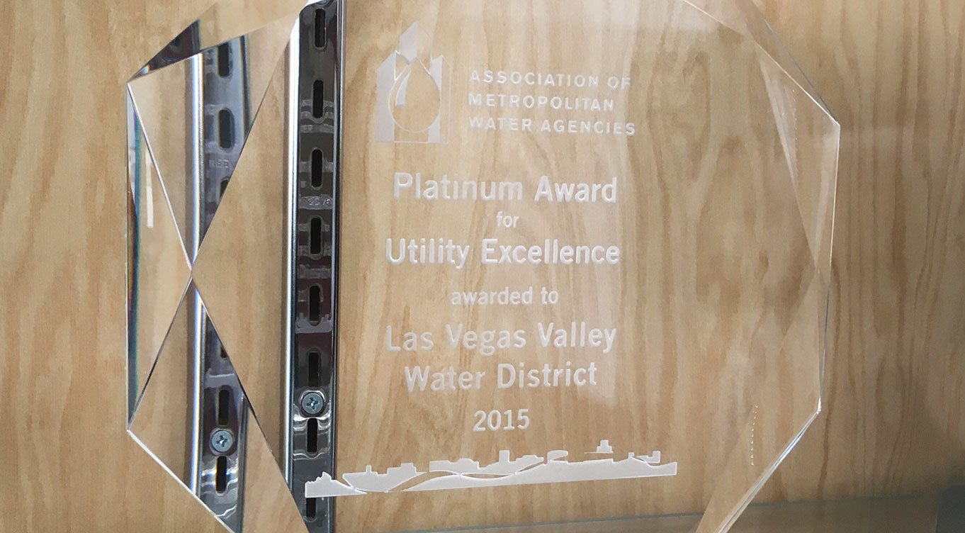 Translucent award plaque engraved with awarded to Las Vegas Valley Water District 2015, in front of wood background.