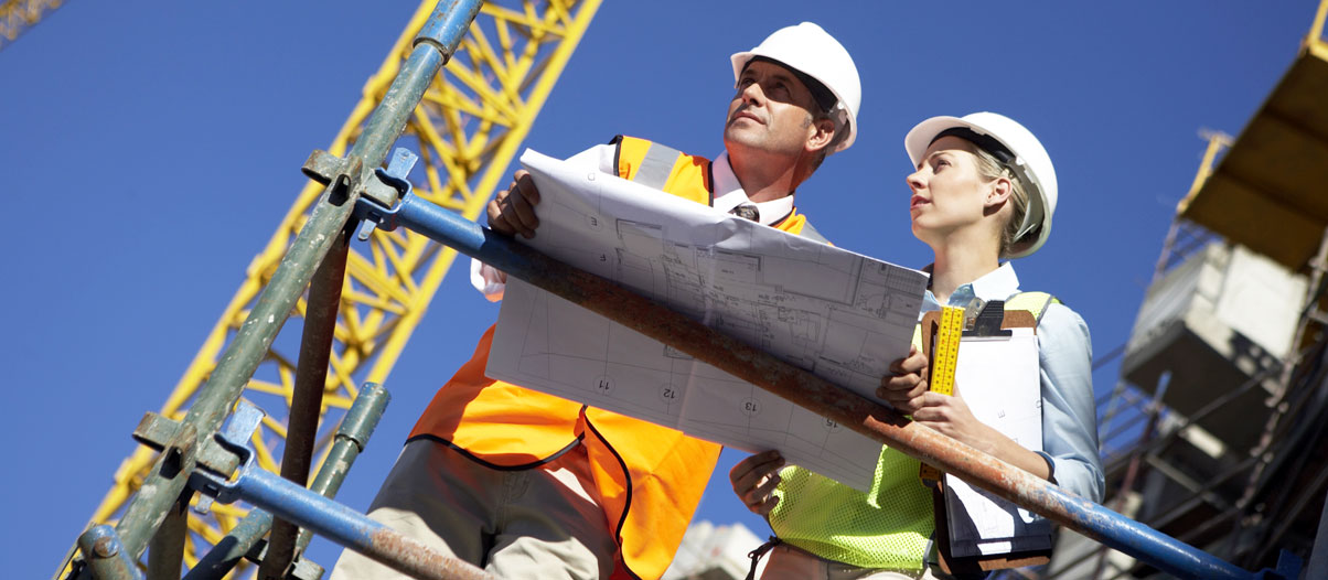 Employees with hard hats surveying a job site.