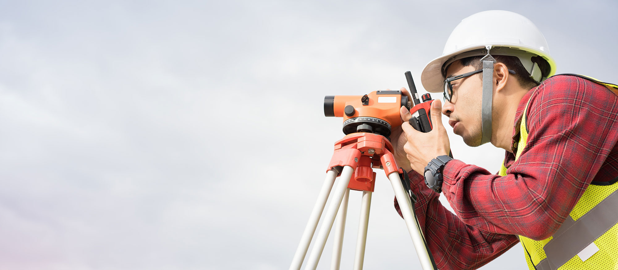 Person wearing hard hat using surveying equipment
