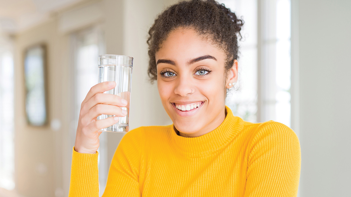Young woman holding a glass of clear water.
