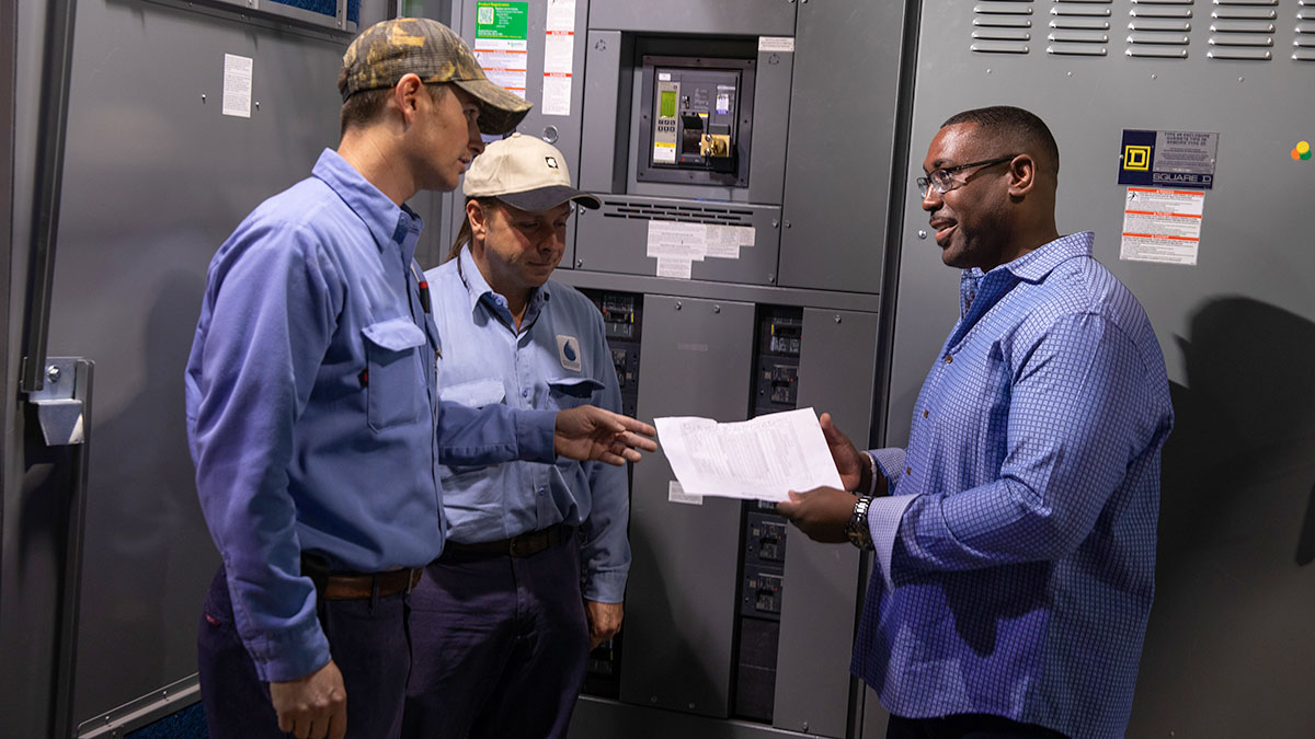 Men standing around control panel