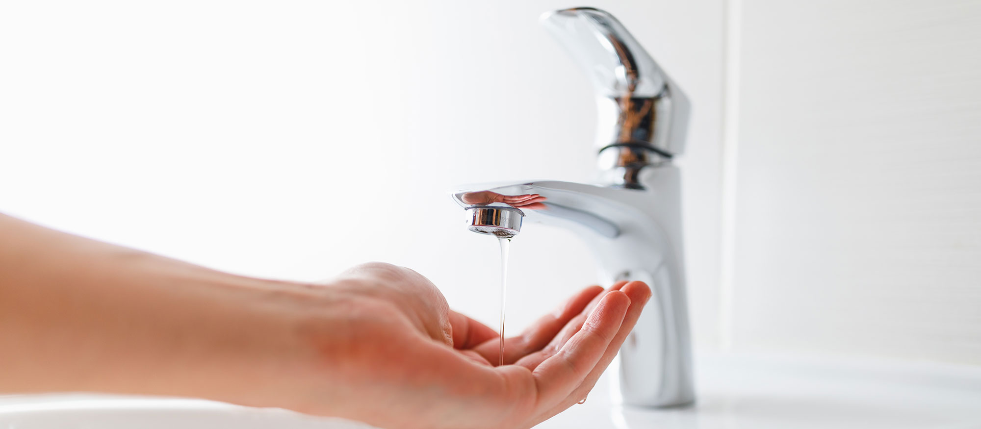 Hand under faucet with low pressure water coming out