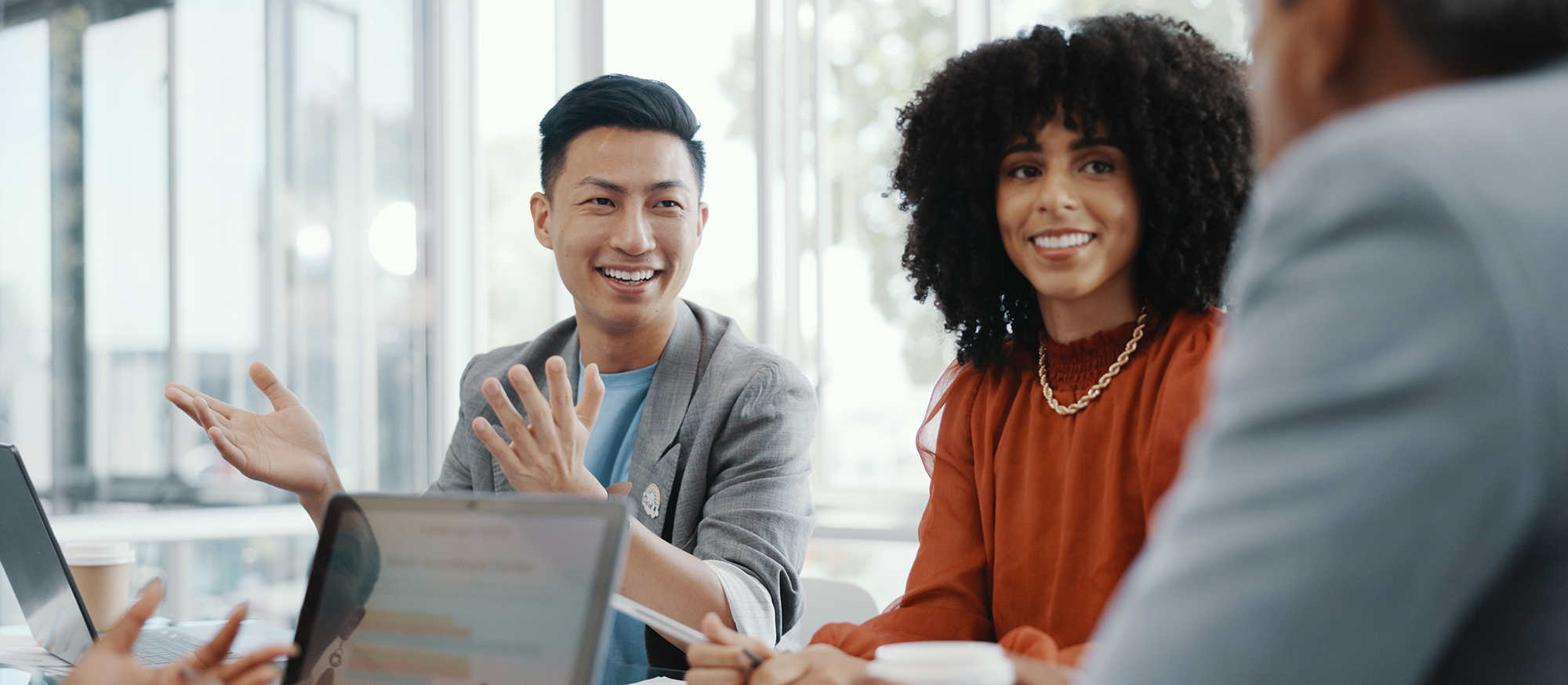 Diverse group at table laugh in front of laptop