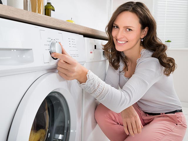 Woman turning knob on washing machine